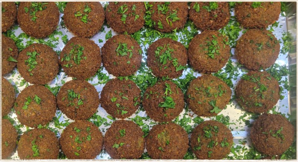 Catering trays of freshly fried falafel topped with chopped parsley