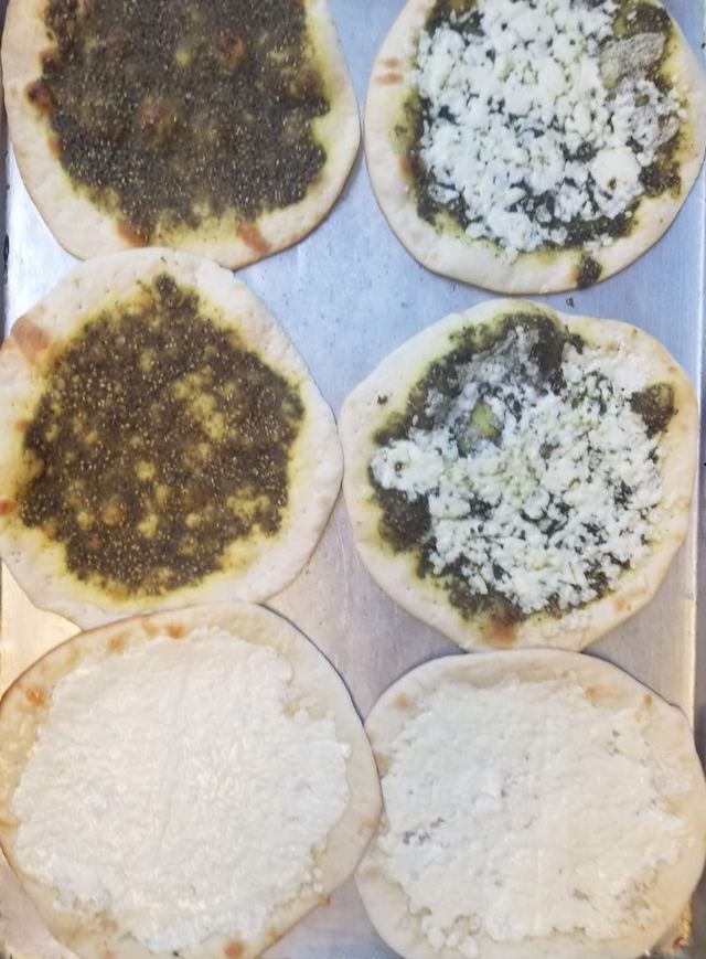 Baking sheet of mini manakish — zaatar, cheese, and cheese-zaatar mix