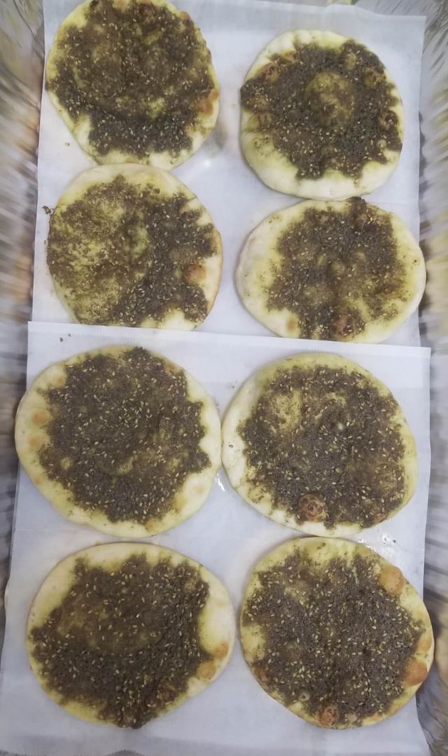 Tray of mini zaatar manakish rounds topped with herbs and sesame