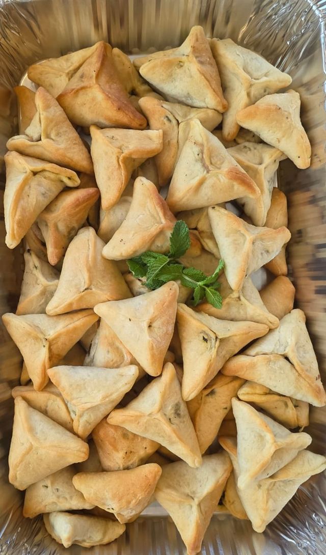 Tray of triangular spinach pies garnished with fresh mint