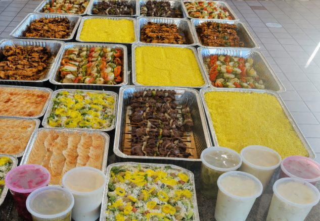 Full Levantine catering buffet line of rice, stews, salads and dips in foil trays